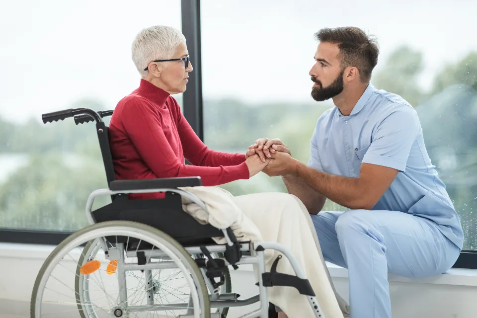 A carer holding the hand of an elderly woman
