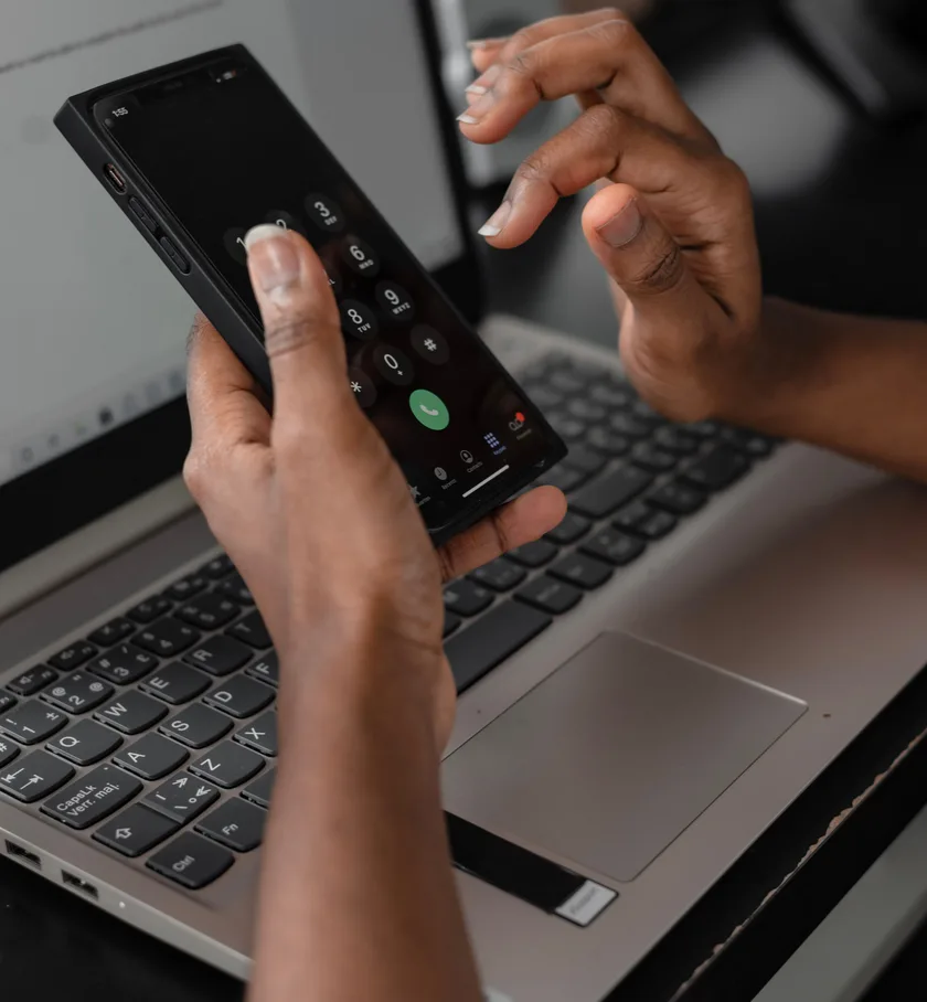 Entering a code on a phone held beside a laptop keyboard