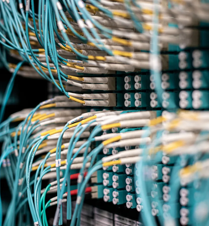 Fibre patch panel with teal and yellow cables in a server cabinet