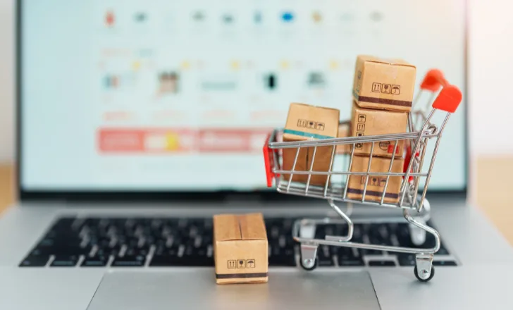 Miniature shopping trolley of parcels on a laptop keyboard