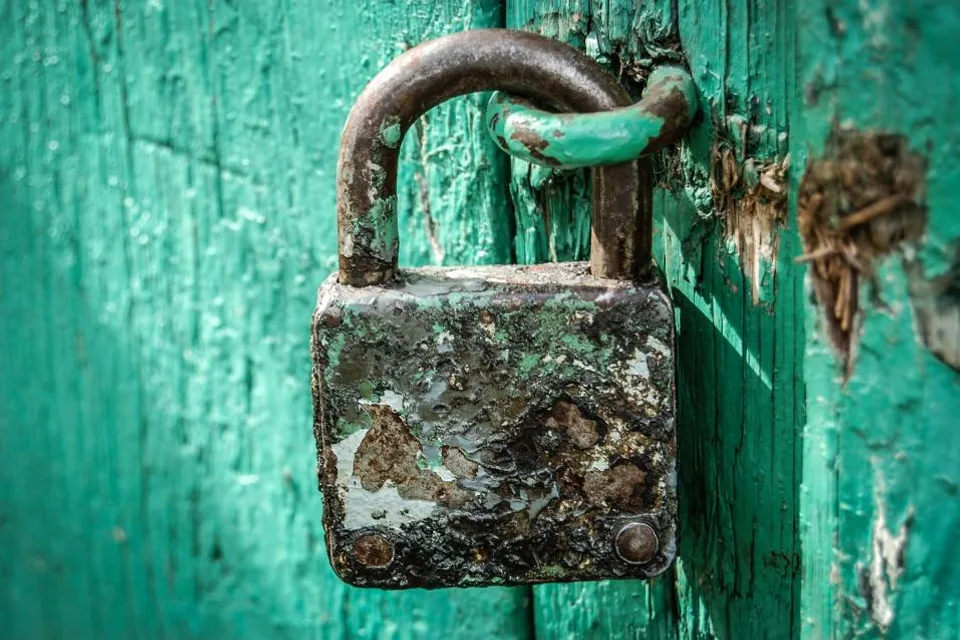 A weathered padlock on a painted door