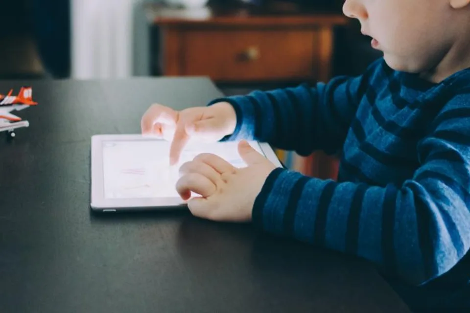 Young child using a tablet at a table