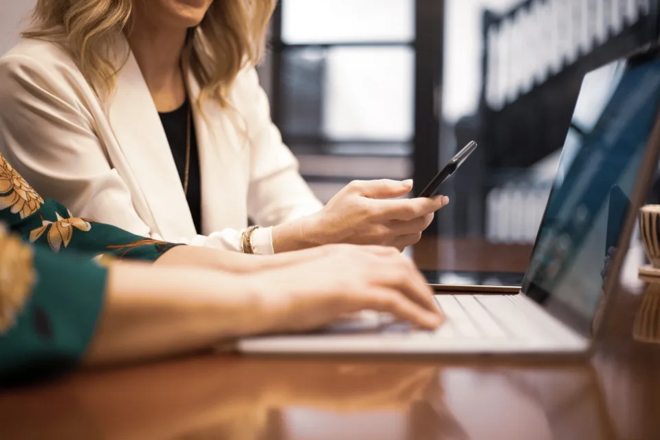 Adviser signing in on a phone while working at a laptop