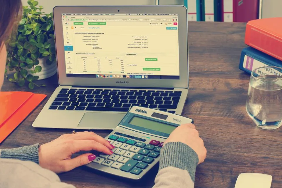 Accountant working through figures on a calculator and laptop