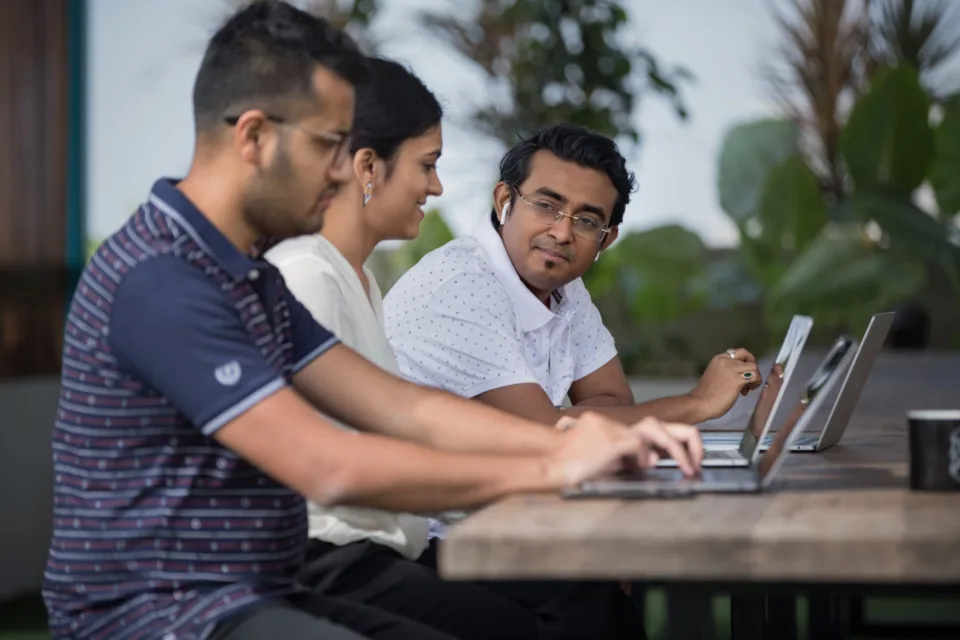 Three colleagues working together at a laptop