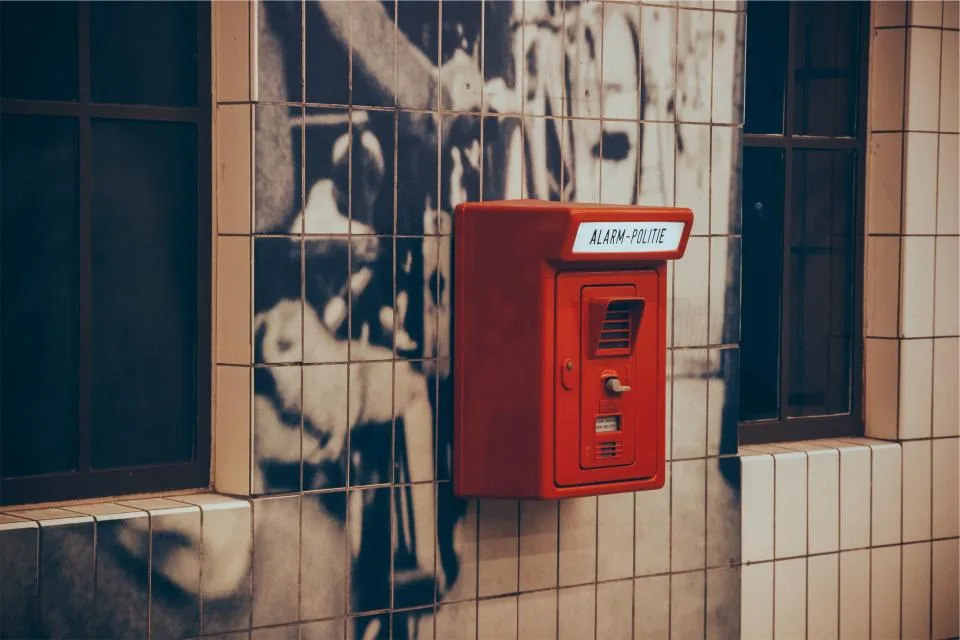 Red alarm call box mounted on a tiled wall