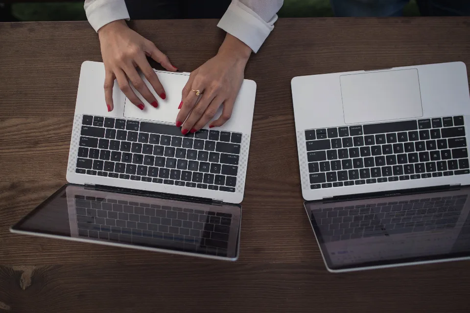 Overhead view of two laptops on a desk, one being typed on