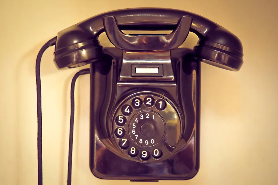 Black rotary dial telephone mounted on a wall