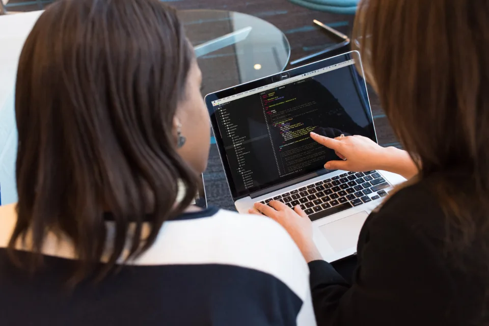 Two developers working through code together on a laptop